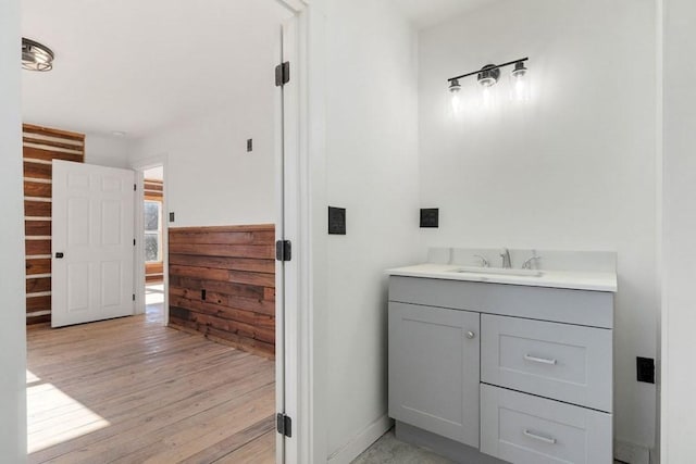 bathroom featuring vanity, wooden walls, and hardwood / wood-style floors