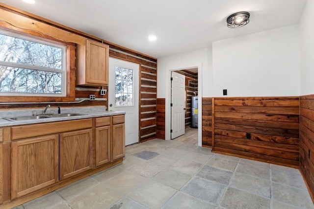 kitchen featuring sink, wooden walls, plenty of natural light, and electric water heater