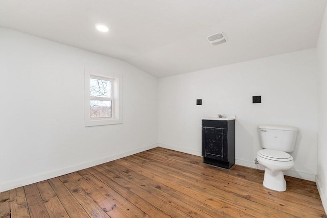 bathroom featuring hardwood / wood-style floors, toilet, vanity, and vaulted ceiling