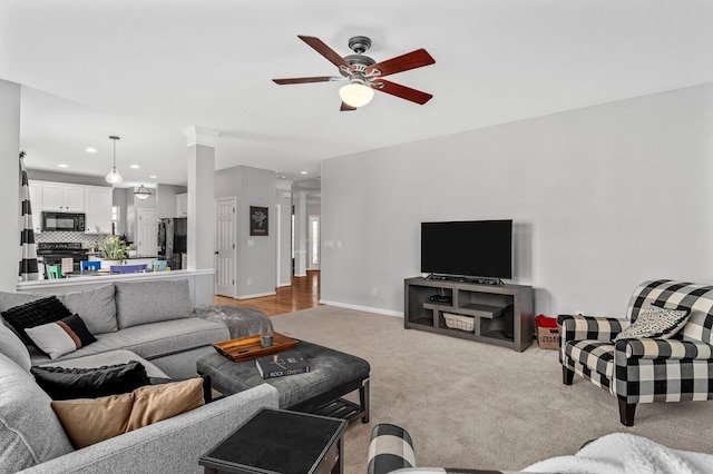 living room featuring ornate columns, light carpet, and ceiling fan