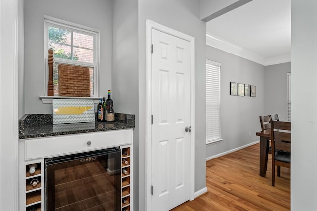 bar featuring ornamental molding, wine cooler, and light hardwood / wood-style floors