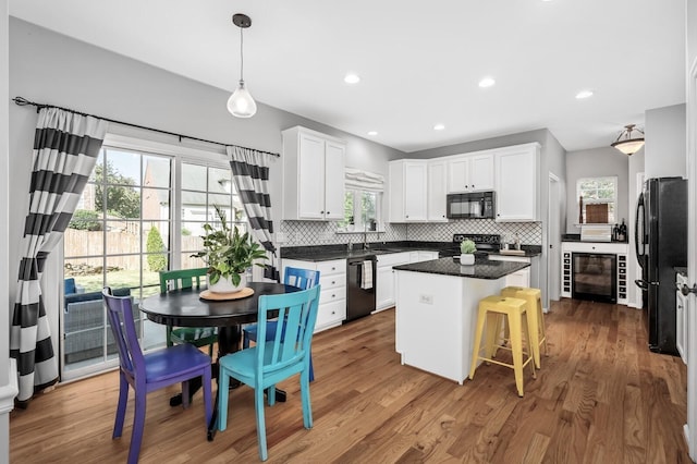 kitchen featuring white cabinetry, wine cooler, black appliances, and a center island