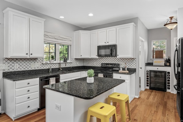 kitchen featuring wine cooler, white cabinets, and black appliances