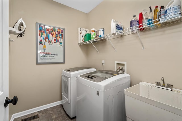 laundry area with independent washer and dryer, dark tile patterned flooring, and sink