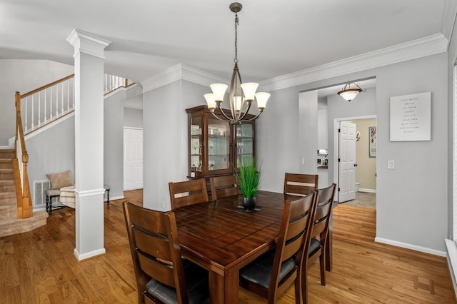 dining space with an inviting chandelier, crown molding, decorative columns, and light hardwood / wood-style floors