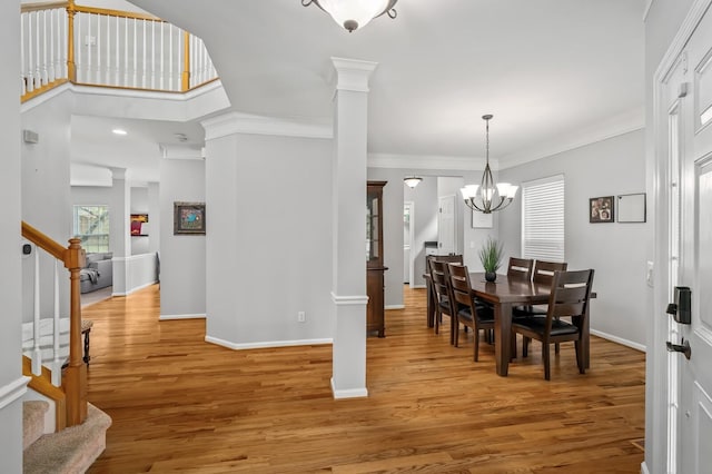 dining room with a notable chandelier, light hardwood / wood-style flooring, ornamental molding, and ornate columns