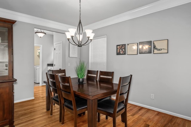 dining space with a notable chandelier, crown molding, and hardwood / wood-style flooring