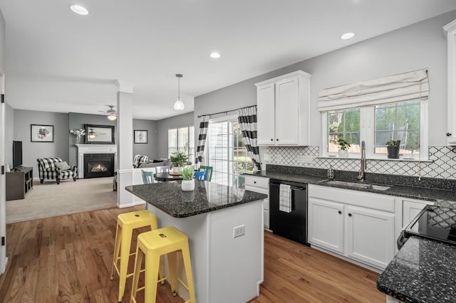 kitchen with sink, dishwasher, a kitchen island, pendant lighting, and white cabinets