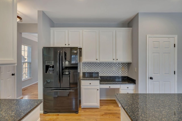 kitchen featuring white cabinetry, dark stone counters, black fridge with ice dispenser, and backsplash