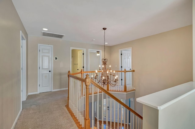 hallway featuring light colored carpet and a notable chandelier