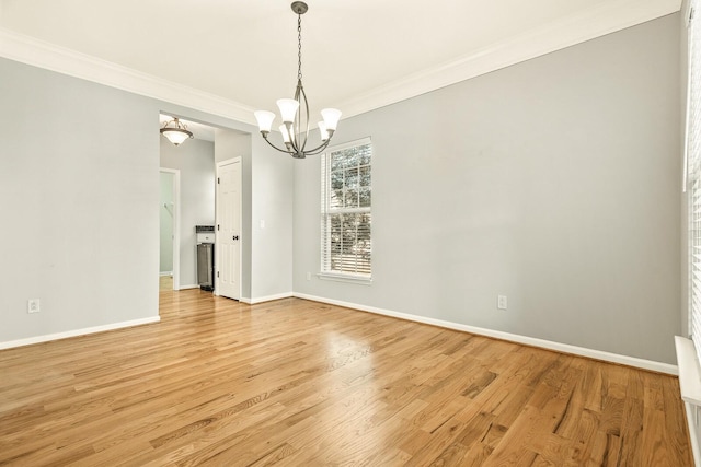 unfurnished dining area featuring light wood-style floors, baseboards, a chandelier, and crown molding