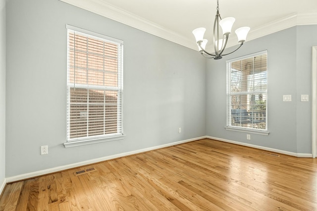 empty room with light wood finished floors, a notable chandelier, visible vents, and crown molding