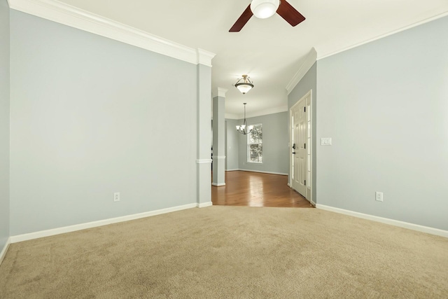 carpeted spare room featuring baseboards, ornamental molding, and ceiling fan with notable chandelier