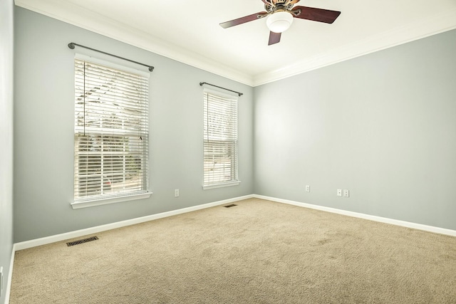 unfurnished room featuring carpet flooring, a ceiling fan, visible vents, baseboards, and ornamental molding