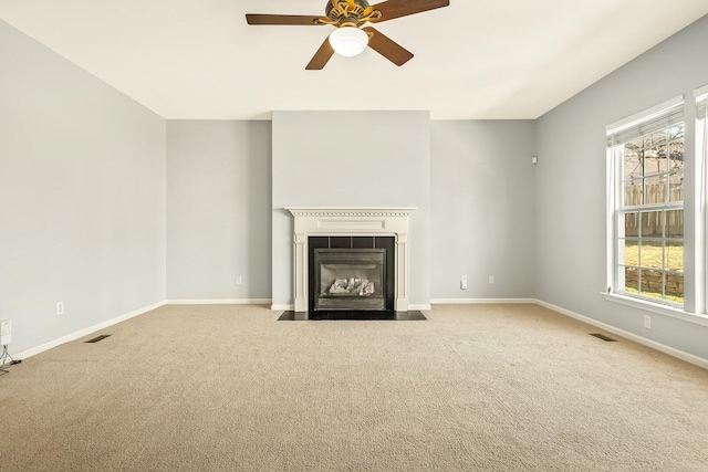 unfurnished living room with visible vents, a tile fireplace, baseboards, and light colored carpet