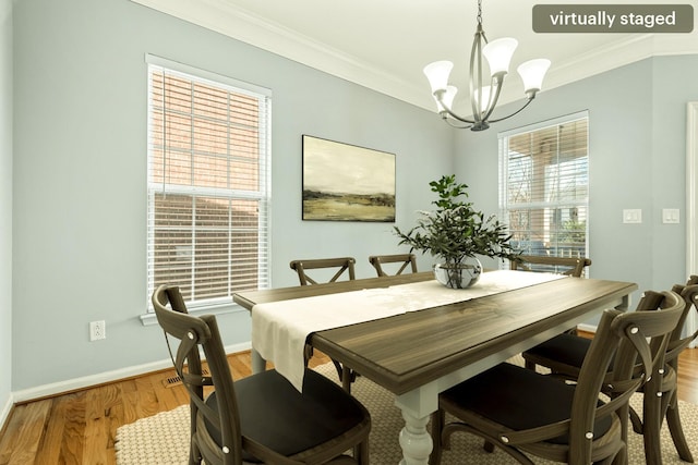 dining room featuring baseboards, ornamental molding, light wood-style flooring, and an inviting chandelier