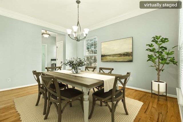 dining space featuring a notable chandelier, ornamental molding, wood finished floors, and baseboards