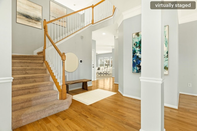 foyer with decorative columns, crown molding, baseboards, and wood finished floors