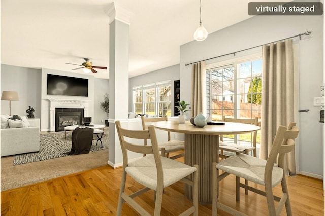 dining room with ceiling fan, plenty of natural light, a glass covered fireplace, and light wood-style floors