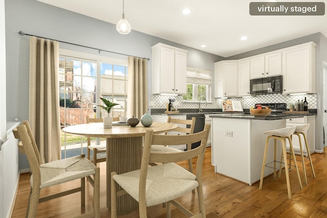 kitchen featuring white cabinets, dark countertops, a kitchen island, hanging light fixtures, and black microwave