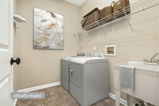 laundry area with baseboards, laundry area, a sink, and washer and dryer