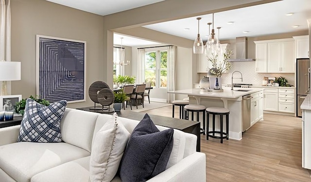 living room featuring an inviting chandelier, sink, and light hardwood / wood-style flooring