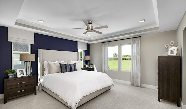 carpeted bedroom with ceiling fan and a tray ceiling