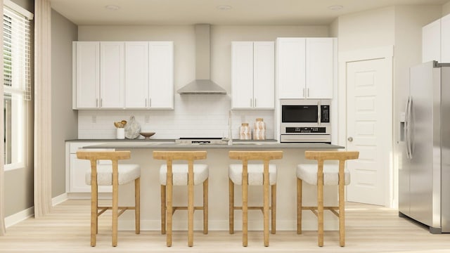 kitchen with wall chimney range hood, white oven, white cabinetry, a kitchen island with sink, and stainless steel fridge with ice dispenser