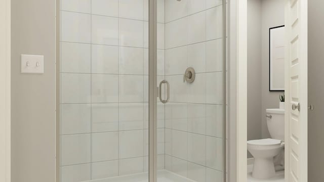 bathroom featuring a shower with shower door and toilet