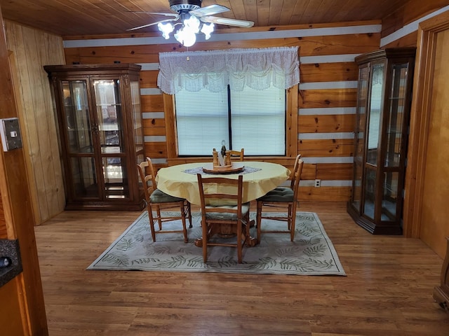 dining area with hardwood / wood-style floors, wooden walls, ceiling fan, and wood ceiling