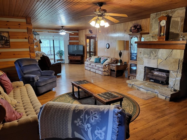 living room with hardwood / wood-style floors, a fireplace, wood ceiling, ceiling fan, and wood walls