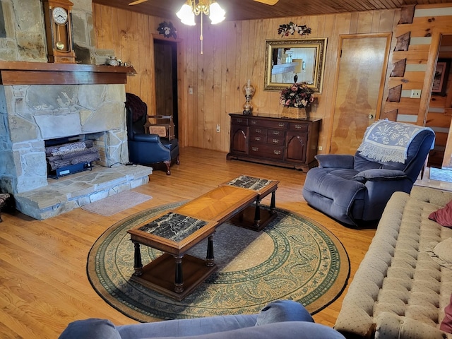 living room with wooden ceiling, light hardwood / wood-style flooring, wood walls, and a fireplace