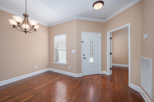 entrance foyer featuring dark hardwood / wood-style flooring, an inviting chandelier, and ornamental molding