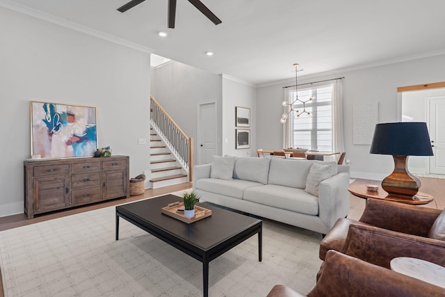 living room featuring light hardwood / wood-style floors, ceiling fan with notable chandelier, and ornamental molding