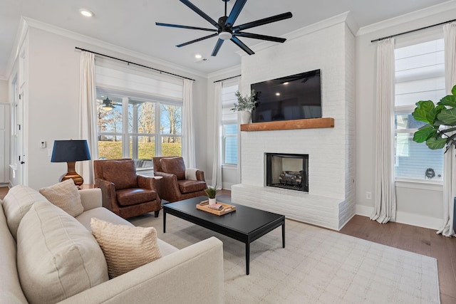 living room featuring a fireplace, light hardwood / wood-style floors, ceiling fan, and ornamental molding