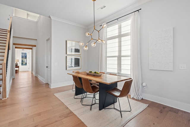 dining area with light hardwood / wood-style flooring, a wealth of natural light, a chandelier, and ornamental molding