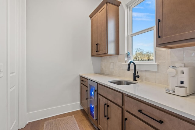 kitchen with decorative backsplash, sink, wine cooler, and light wood-type flooring