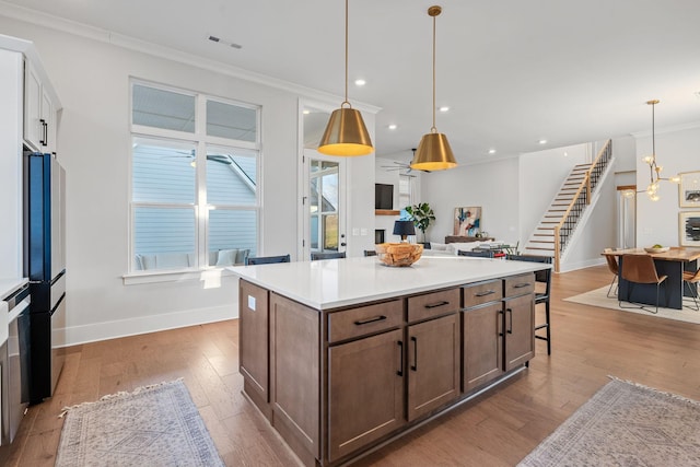 kitchen with white cabinetry, hanging light fixtures, crown molding, and a kitchen island