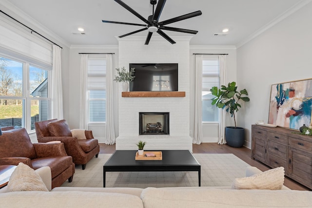 living room with ornamental molding, ceiling fan, light hardwood / wood-style flooring, and a fireplace