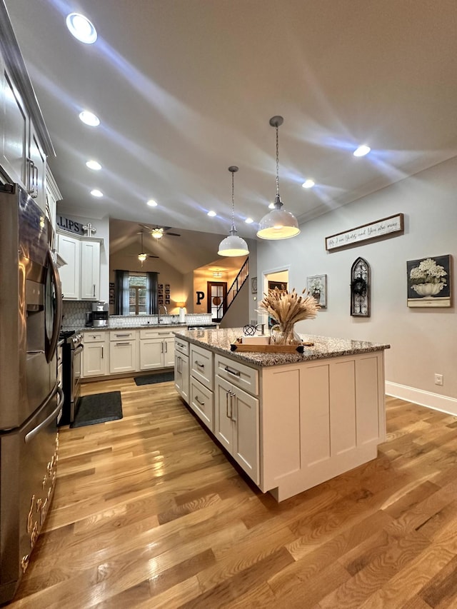 kitchen featuring appliances with stainless steel finishes, a center island, decorative light fixtures, decorative backsplash, and kitchen peninsula