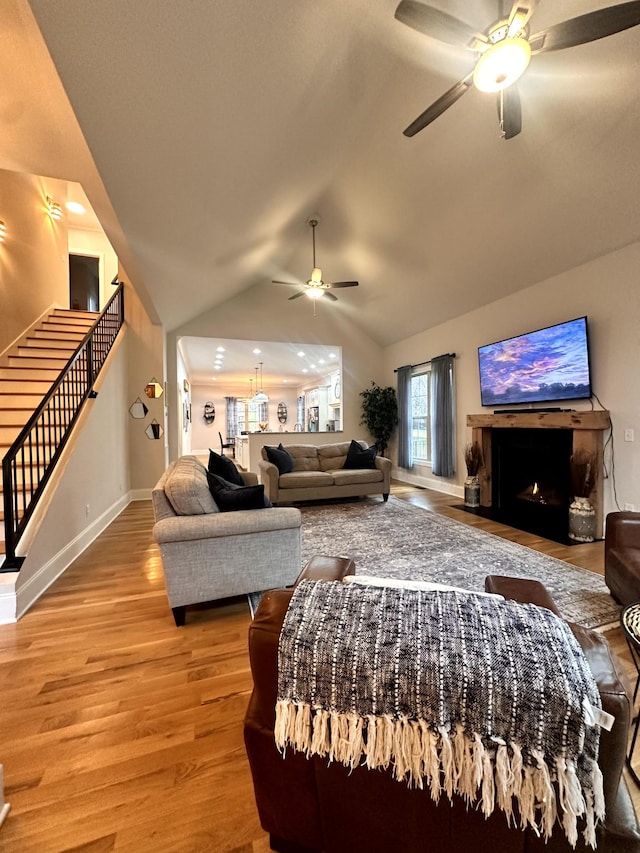 living room with ceiling fan, lofted ceiling, and light wood-type flooring