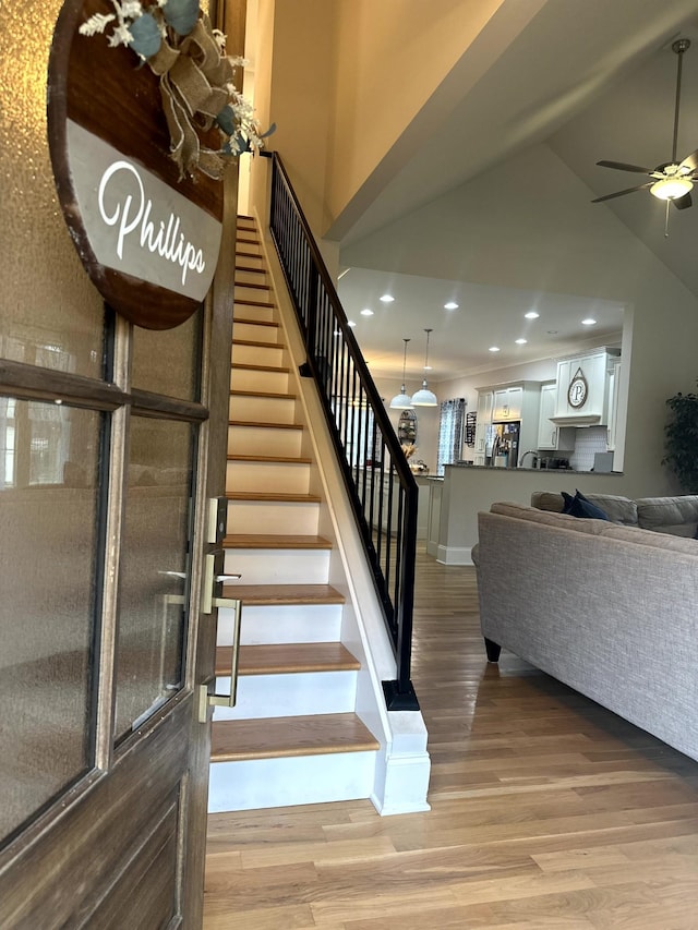 staircase with ceiling fan and hardwood / wood-style floors