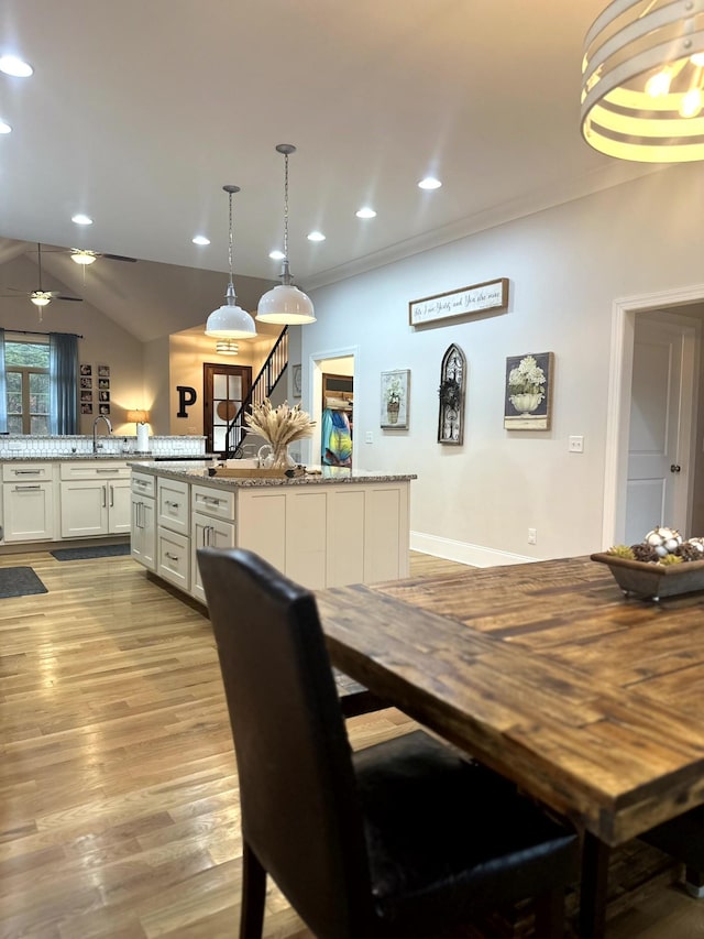 dining area featuring sink, lofted ceiling, and light wood-type flooring