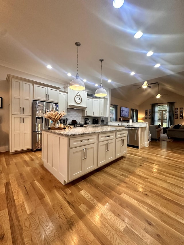 kitchen with light hardwood / wood-style floors, appliances with stainless steel finishes, decorative backsplash, a kitchen island, and pendant lighting