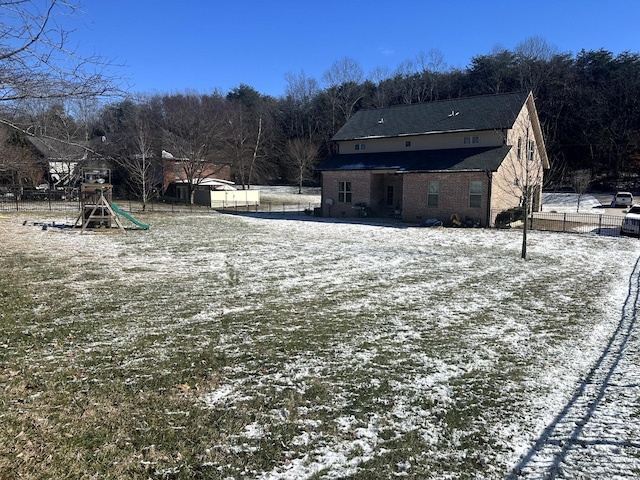 yard covered in snow featuring a playground