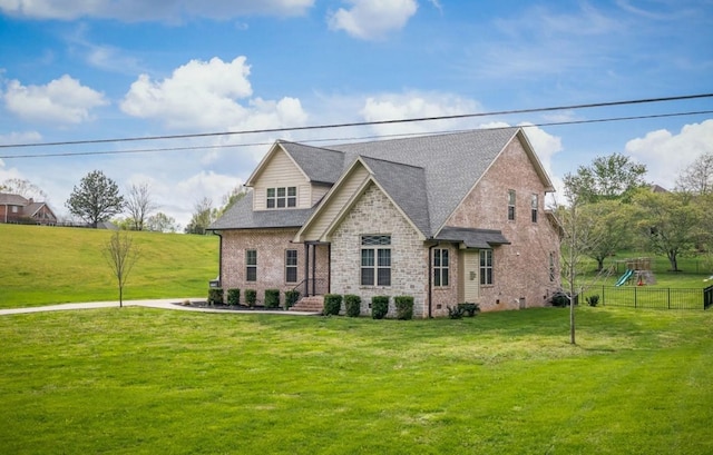 view of front of property with a front yard, a shingled roof, brick siding, and a playground