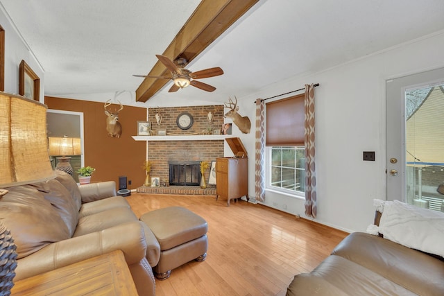 living room with a brick fireplace, hardwood / wood-style flooring, ceiling fan, and vaulted ceiling with beams