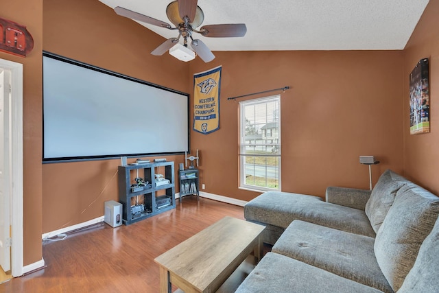 home theater featuring hardwood / wood-style flooring, ceiling fan, and vaulted ceiling