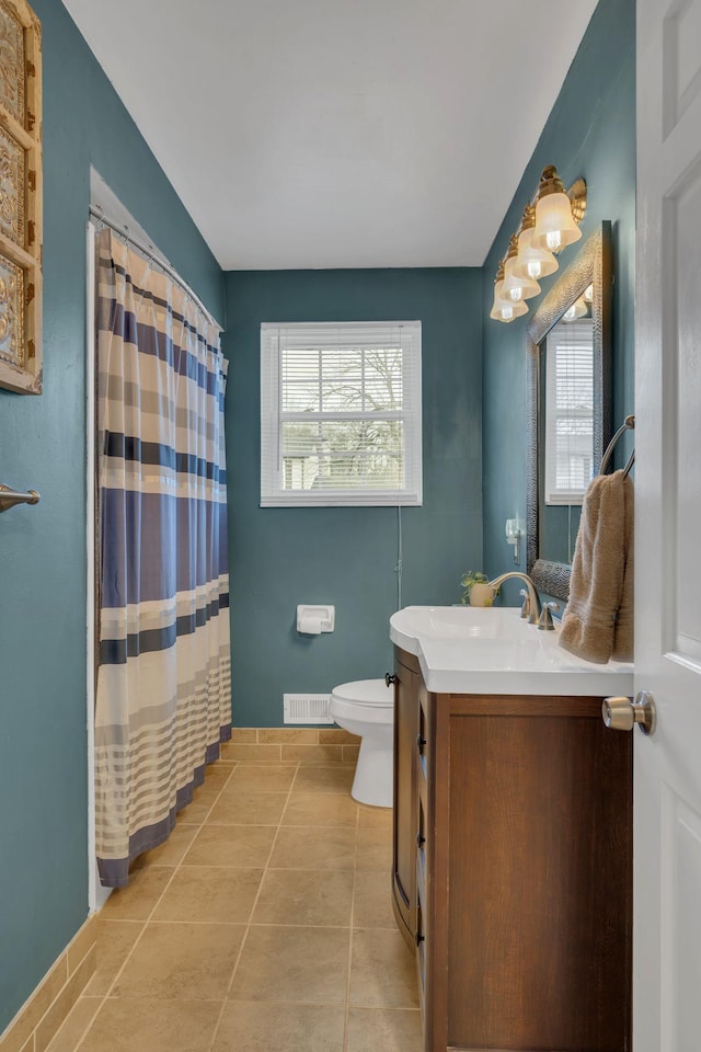 bathroom featuring vanity, toilet, a healthy amount of sunlight, and tile patterned floors