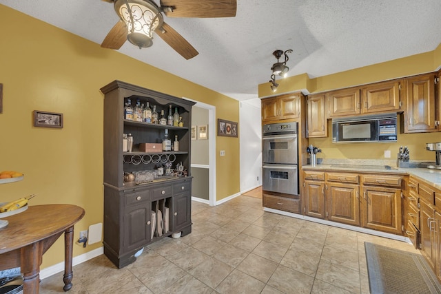 kitchen with cooktop, ceiling fan, double oven, and a textured ceiling